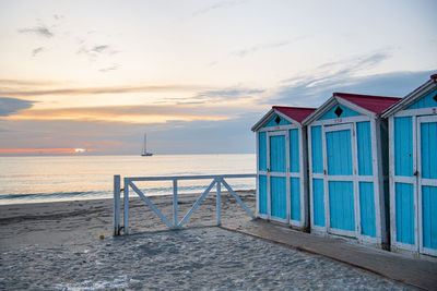 Little blue houses on the beach. a place to store beach utensils. sunset on the mediterranean coast.