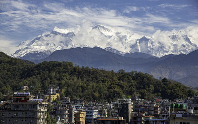 Panoramic view of townscape and mountains against sky