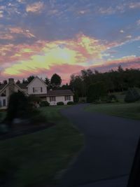 Scenic view of field against cloudy sky at sunset