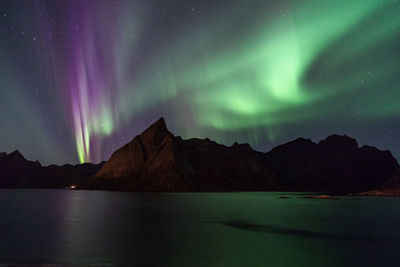 Scenic view of lake and mountains against sky at night