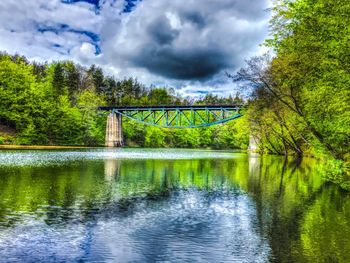 Bridge over river against cloudy sky