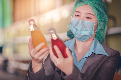 Close-up of woman wearing mask inspecting drinks in factory