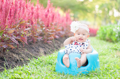 Portrait of cute girl sitting on potty at yard