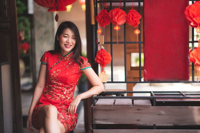 Smiling woman wearing red dress sitting outdoors