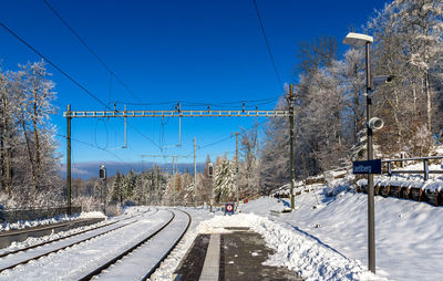 Railroad tracks by snowcapped mountain against sky