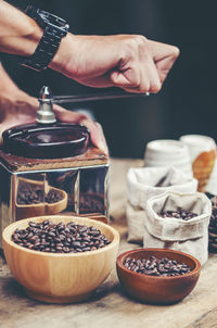 Cropped hands grinding roasted coffee beans at table