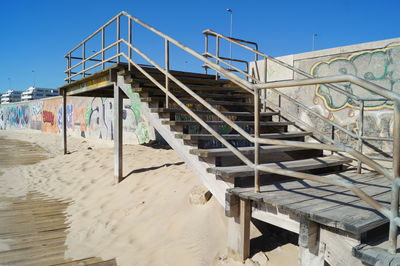Staircase on beach against clear blue sky
