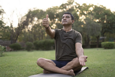 Young man sitting on grass against plants