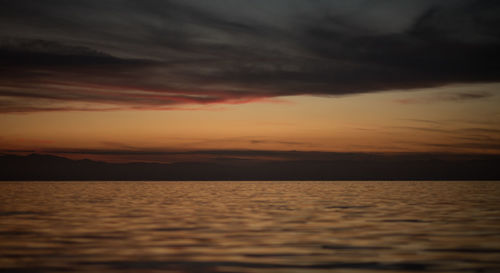 Scenic view of sea against dramatic sky during sunset