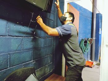Side view of man working against wall