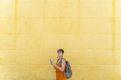 Woman using mobile phone against wall