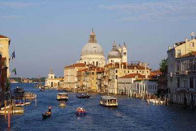 Boats in canal amidst buildings against sky in city