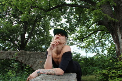 Low angle view of woman sitting against trees