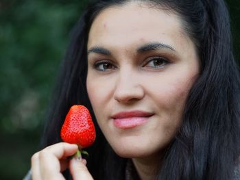Close-up portrait of woman holding strawberry