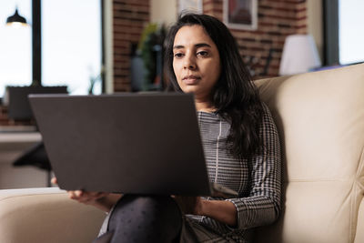 Portrait of young woman using laptop at home