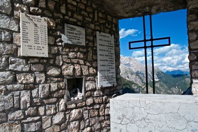 Text on wall by building against sky