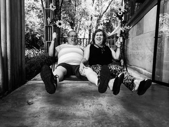 Portrait of happy friends swinging in porch