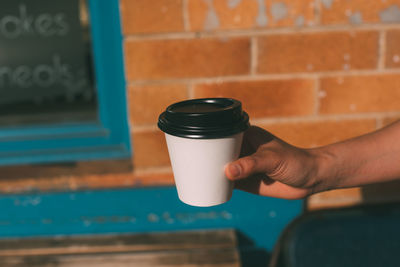 Midsection of man holding glass against wall