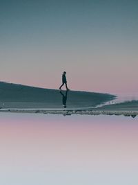 Full length of man on sea against sky during sunset