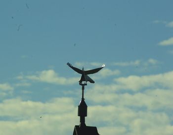 Low angle view of communications tower against cloudy sky