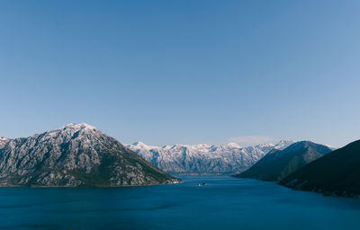 Scenic view of sea and mountains against clear blue sky