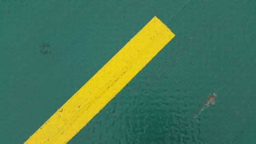 High angle view of yellow arrow sign on road