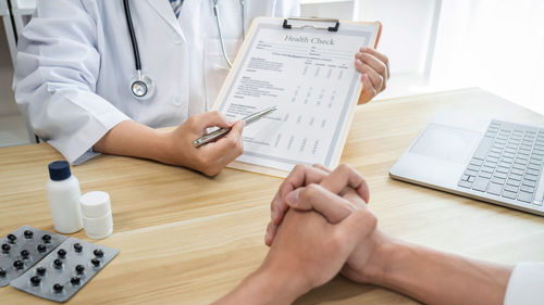 Midsection of doctor examining patient in office