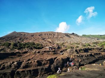 People on mountain against blue sky