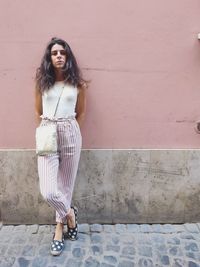 Portrait of young woman standing against wall