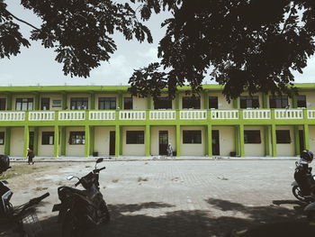 Building by trees in city against sky