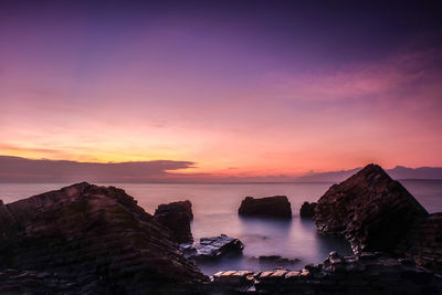 Scenic view of sea and rocks at sunset