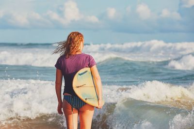 Rear view of young woman standing at beach