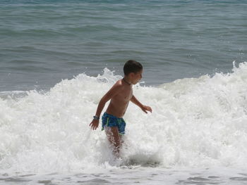 Full length of shirtless boy in sea