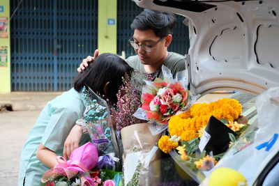 Couple with flower bouquets at car trunk