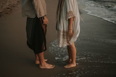 Low section of couple standing on beach