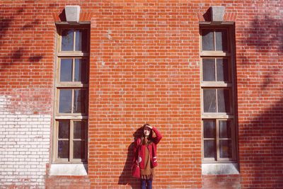 Portrait of woman standing against brick wall