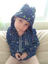 Close-up portrait of girl sitting against wall