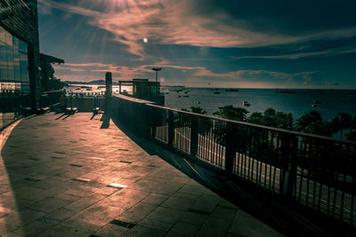 Footpath by sea against sky during sunset