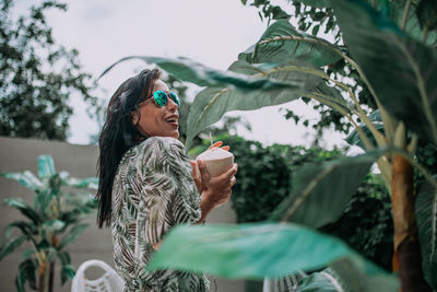 Young woman drinking water from plant