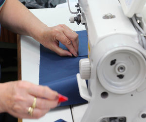 Midsection of tailor using sewing machine while stitching textile