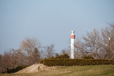 Lighthouse amidst trees against clear sky