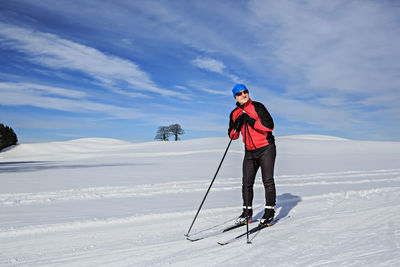 Full length of man skiing on snowy field against sky