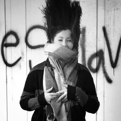 Portrait of smiling young woman standing against wall
