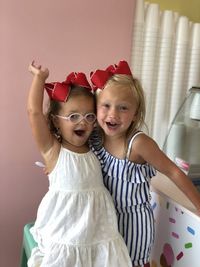 Portrait of girl with sister standing at home