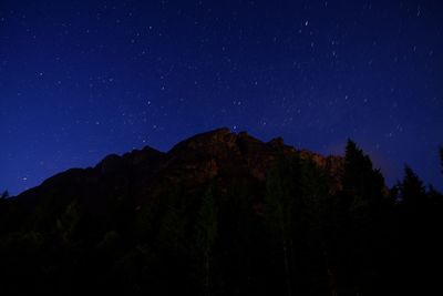 Low angle view of trees against mountain at night