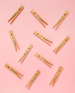 Wooden clothes pins on a pink background.