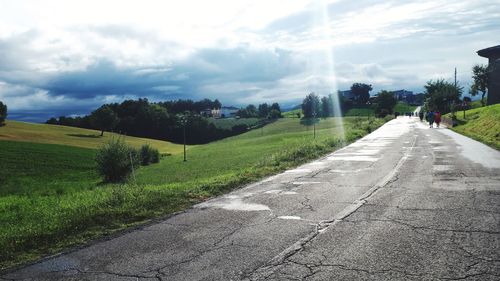 Road amidst trees on field against sky