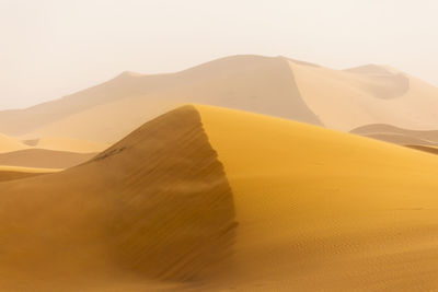 Scenic view of desert against clear sky during sunny day