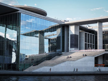 People at paul-lobe-haus by spree river against sky