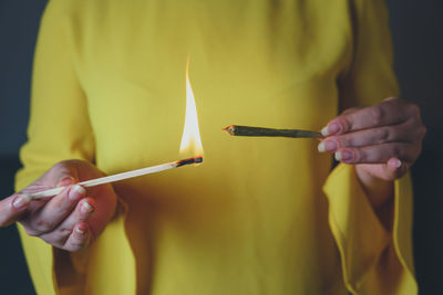 Midsection of woman holding lit candle